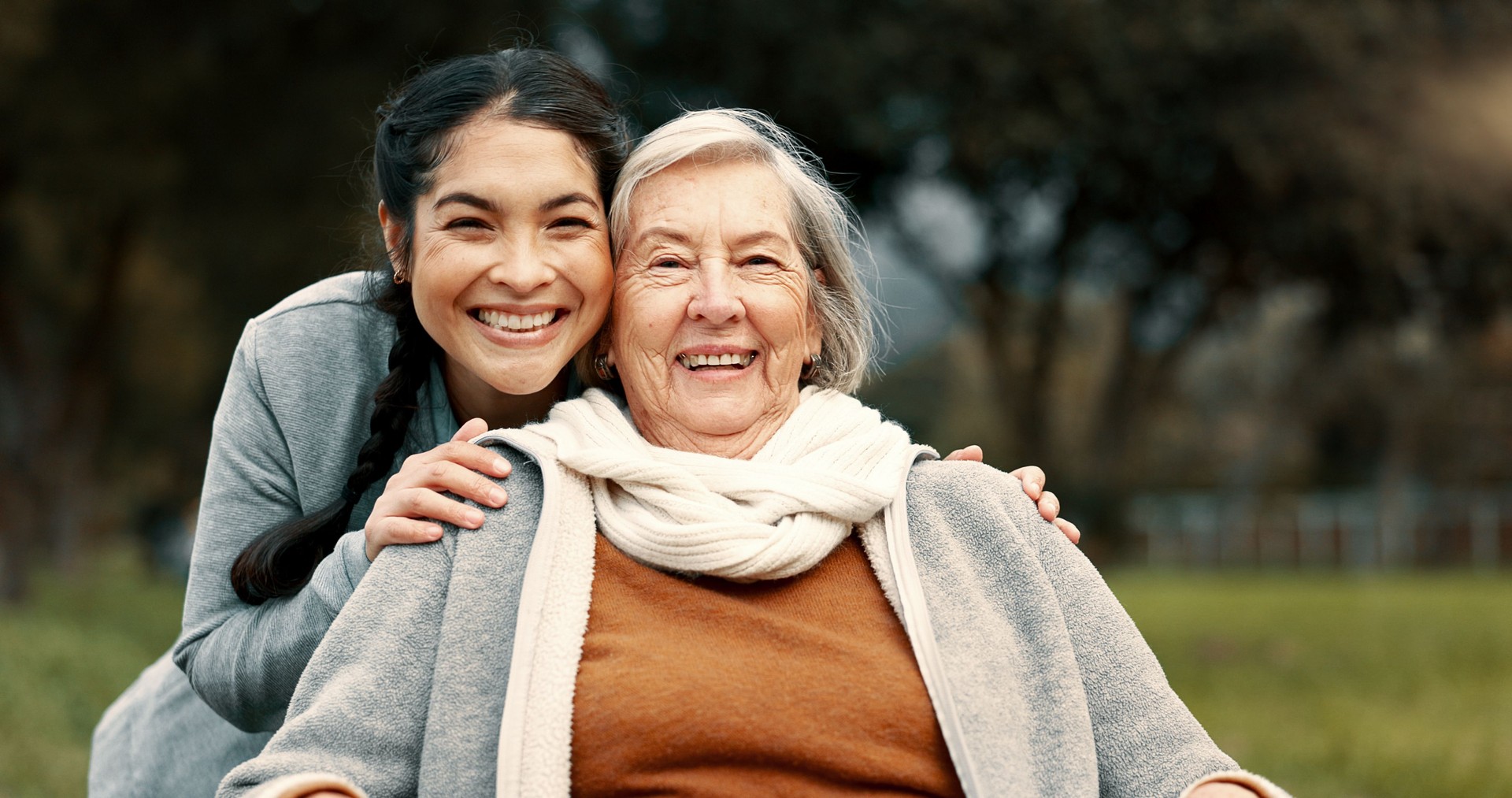 Portrait, senior woman and outdoor with caregiver, nurse or healthcare service for person with a disability and wheelchair. Happy, face and elderly lady in park with care and support in retirement